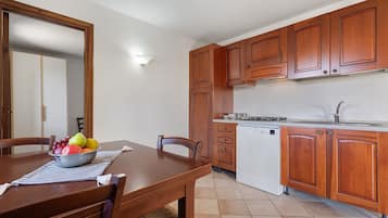 Una cucina con mobili in legno, un'lavastoviglie bianca e un tavolo da pranzo con sedie.