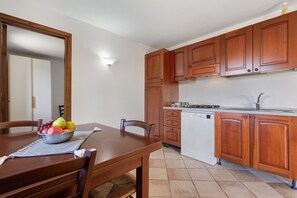 Una cocina con armarios de madera, un lavavajillas blanco y una mesa de comedor con sillas.