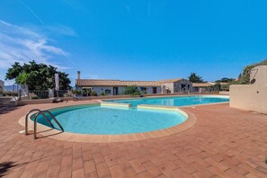 Un espace piscine comprenant deux piscines, un patio couvert et un bâtiment doté d’un toit en tuiles.