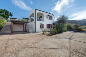 A two-story house with a garage, a staircase, and a view of the surrounding landscape.