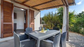 An outdoor patio with wicker furniture, a table, and a thatched roof.