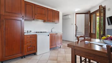 Una cucina con mobili in legno, lavastoviglie integrata e zona pranzo con tavolo e sedie.