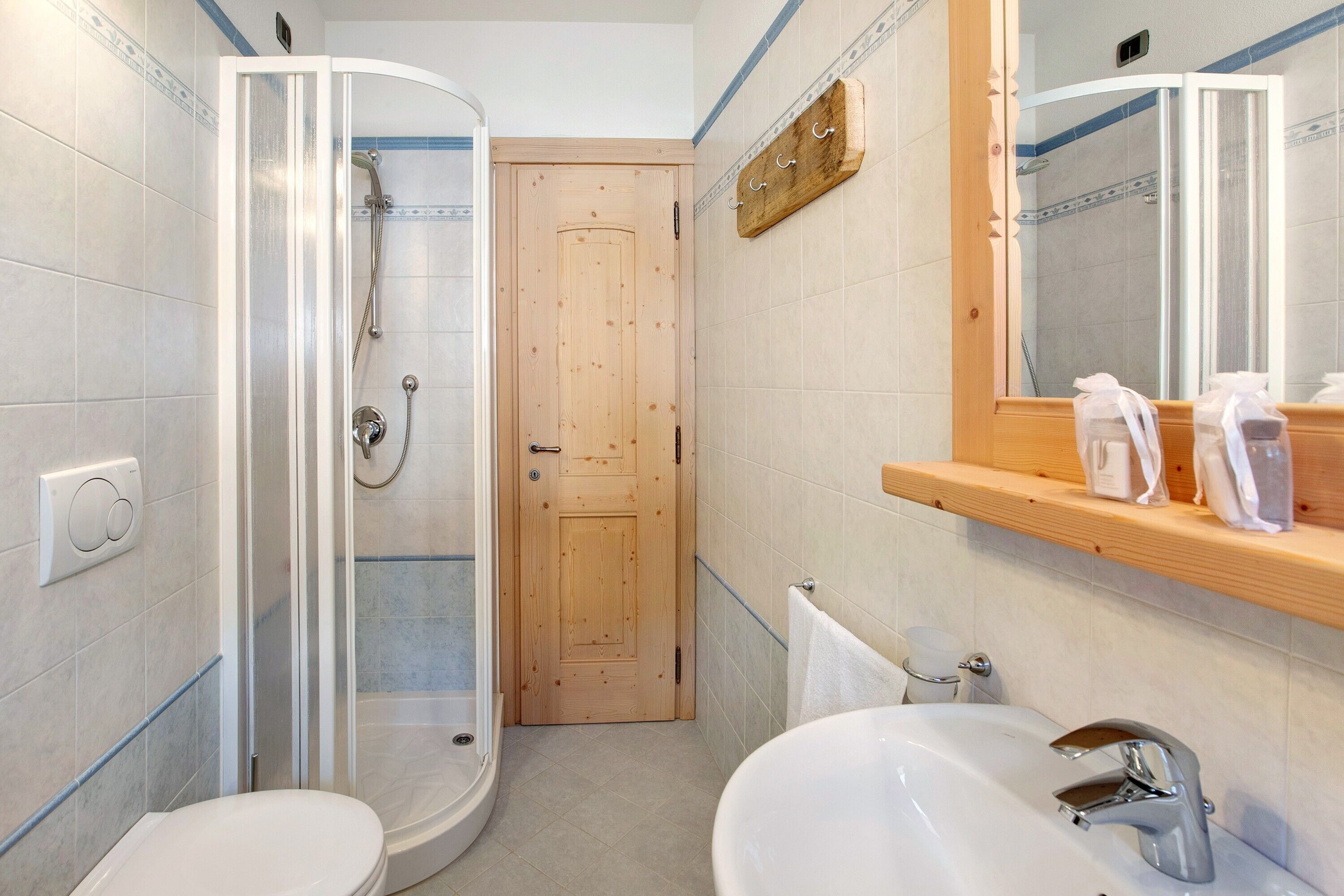 Et badeværelse med bruser, toilet, vask og en trædør.