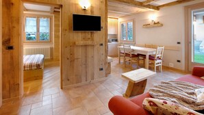 Un interior de madera con una cama, un televisor, un comedor y un sofá rojo.