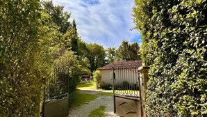 A gated entrance with a gravel path leading to a building with a tiled roof. - Mon Gîte en Provence - Fantastic Villa with Pool, Grand Piano and Fireplace in the Green Provence (Salernes)
