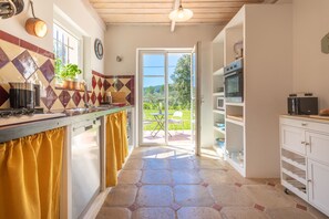 Una cocina con vistas al exterior, un comedor y un armario blanco.