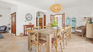 A spacious dining area with a wooden table, wicker chairs, and a hanging light fixture. - Mon Gîte en Provence - Fantastic Villa with Pool, Grand Piano and Fireplace in the Green Provence (Salernes)