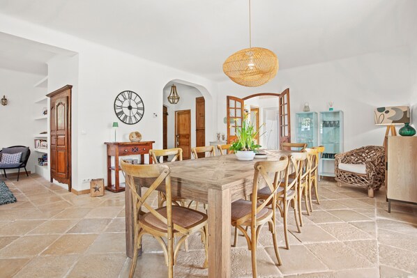 Un comedor amplio con una mesa de madera, sillas de mimbre y una lámpara colgante.