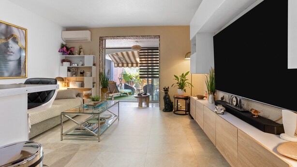 Un salon moderne comprenant un canapé, une table basse, un téléviseur et des objets de décoration.