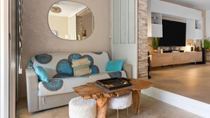 Un salon avec un canapé, une table basse, un miroir et un téléviseur à l’arrière-plan.