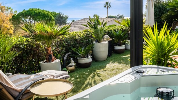 Une terrasse dotée d’un jacuzzi, de chaises longues et de plantes en pot.