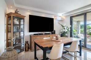 Ein Essbereich mit Holztisch, zwei Stühlen, einem großen Flachbildfernseher und einer Vitrine.