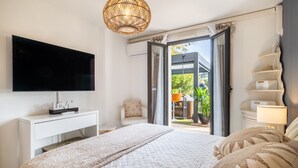 Une chambre à coucher comprenant un lit, une télévision, une table de chevet, une lampe et une vue sur l’extérieur.