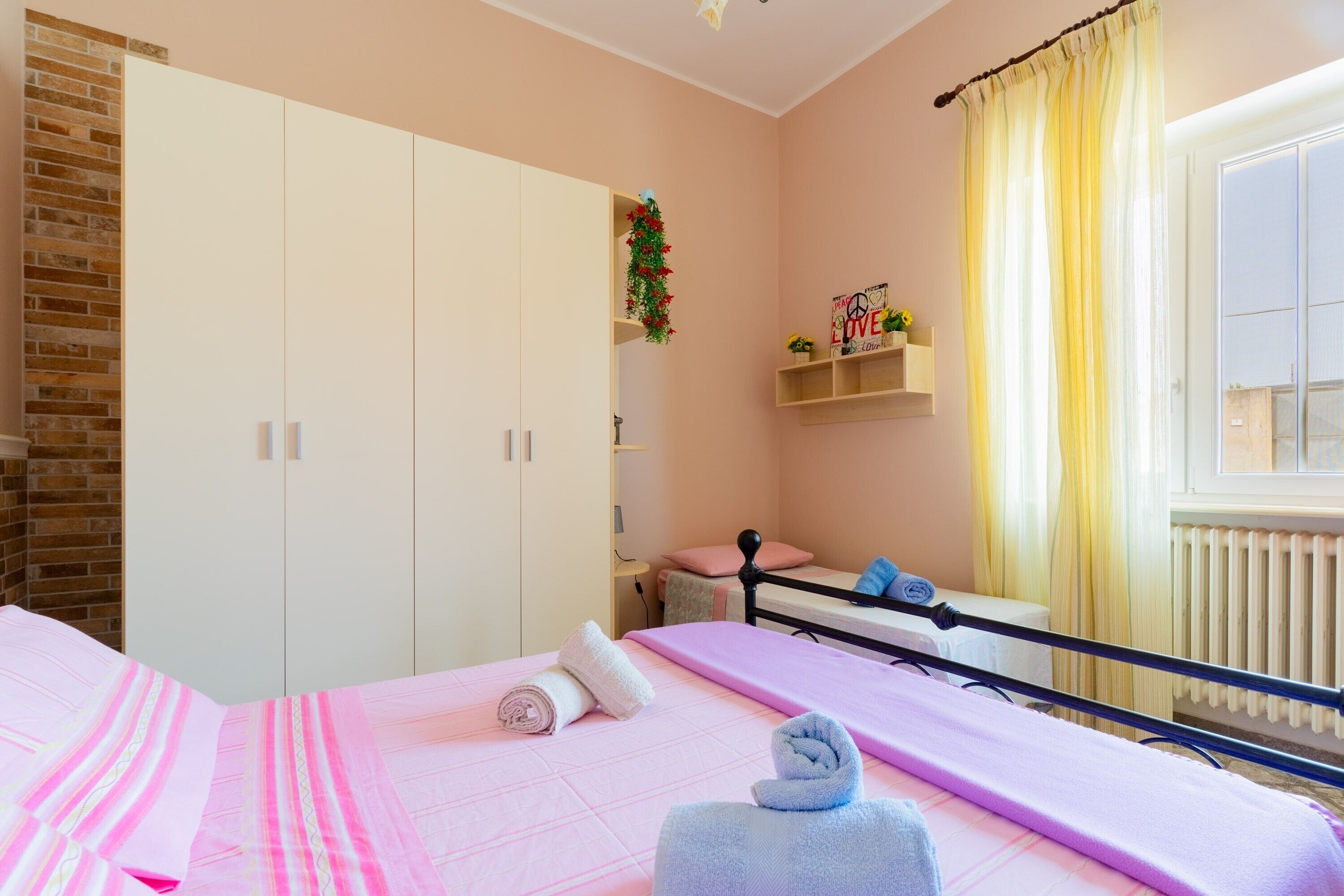 Una camera da letto con un letto, un armadio, uno scaffale con oggetti decorativi e una finestra con tende.