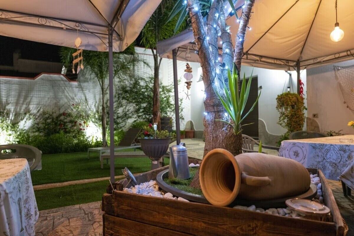An outdoor patio area with a covered seating area, a decorative tree trunk, and a rustic wooden barrel.