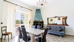 Zona pranzo con tavolo e sedie, un divano, un caminetto e un lampadario.