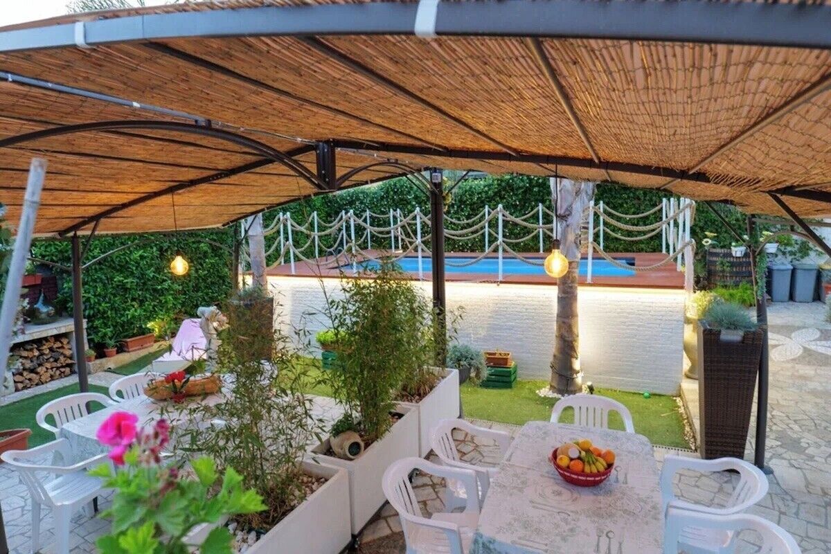 An outdoor patio with a table, chairs, and a pool in the background.