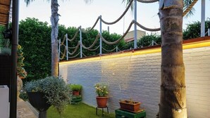 Un piccolo giardino recintato con un muro in mattoni, una palma e piante in vaso.