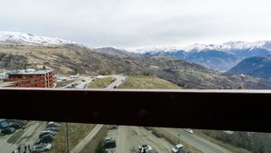 Un paisaje montañoso con una carretera, un estacionamiento y un edificio de fachada roja.