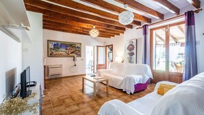 Une pièce chaleureuse avec un plafond en bois, un canapé blanc, une petite table et un tableau accroché au mur.