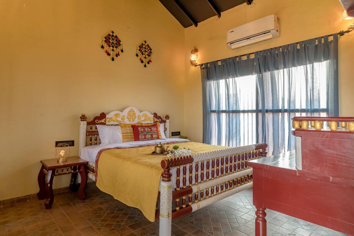 A neatly arranged bedroom with a bed, bedside tables, a dresser, and a window with curtains.