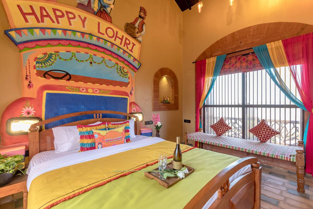 A colorful room with a bed, a bench, and a window with curtains.
