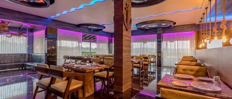 Un restaurant au décor moderne, avec des tables et des chaises en bois, et une colonne centrale.