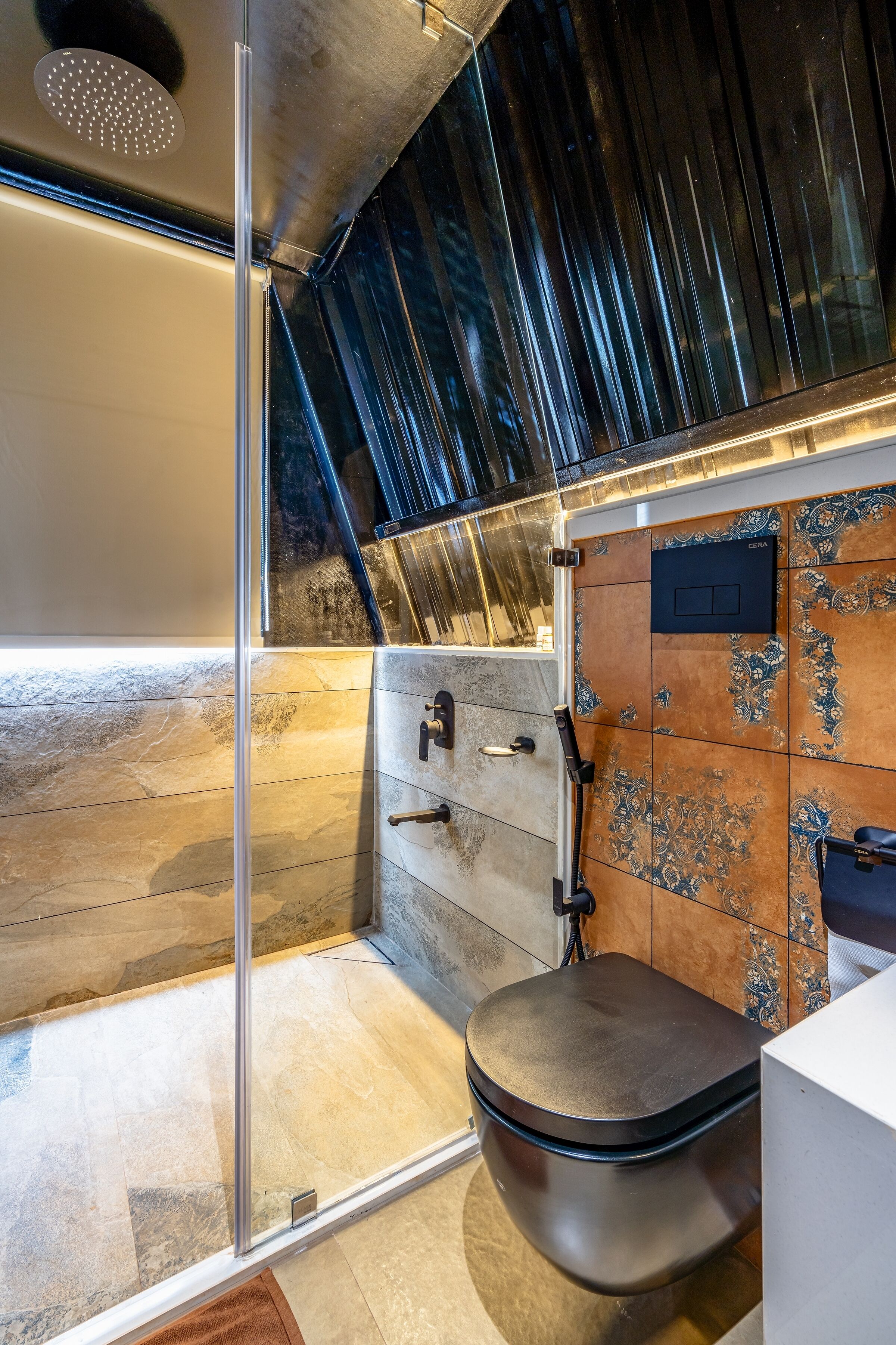 A modern bathroom with a glass shower enclosure, a toilet, and a vanity with a decorative tile backsplash.
