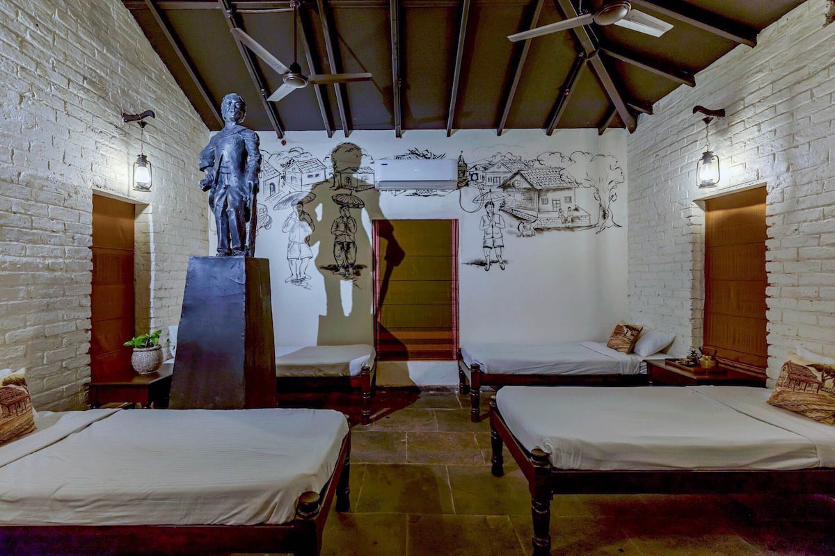 A room with two beds, a statue, and a mural on the wall.