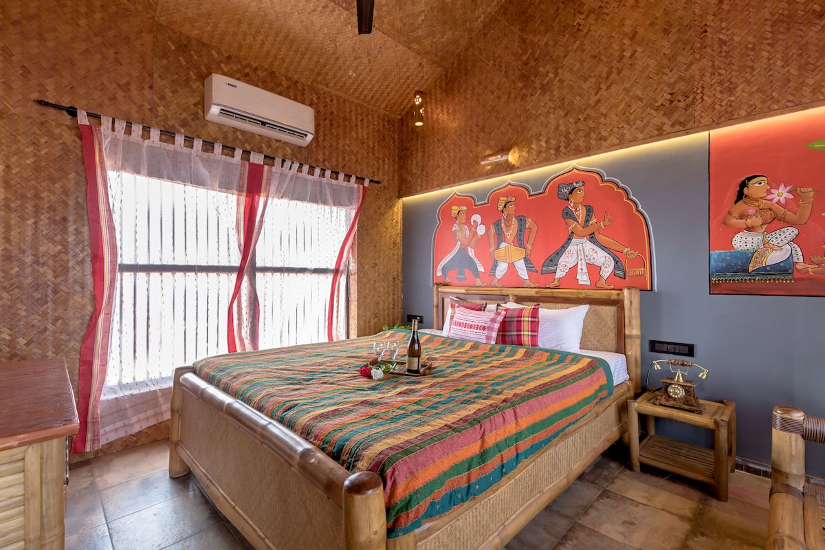 A traditional room with a bed, a nightstand, and a wall with cultural artwork.