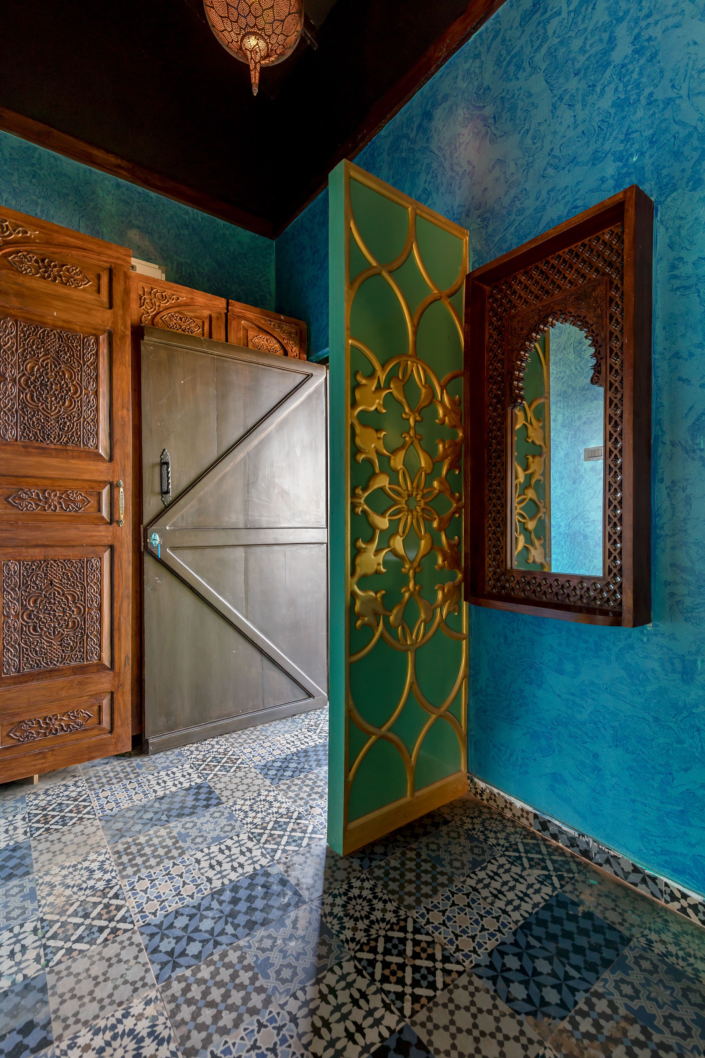 Une pièce dotée d’une grande porte en bois, d’un panneau décoratif et d’un miroir encadré d’un cadre orné.