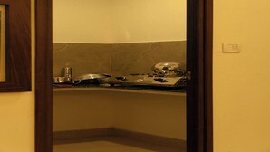 A small kitchen with a stove, a kettle, and a microwave. - Flora Pavillion Near Global Hospital Perumbakkam (Chennai)