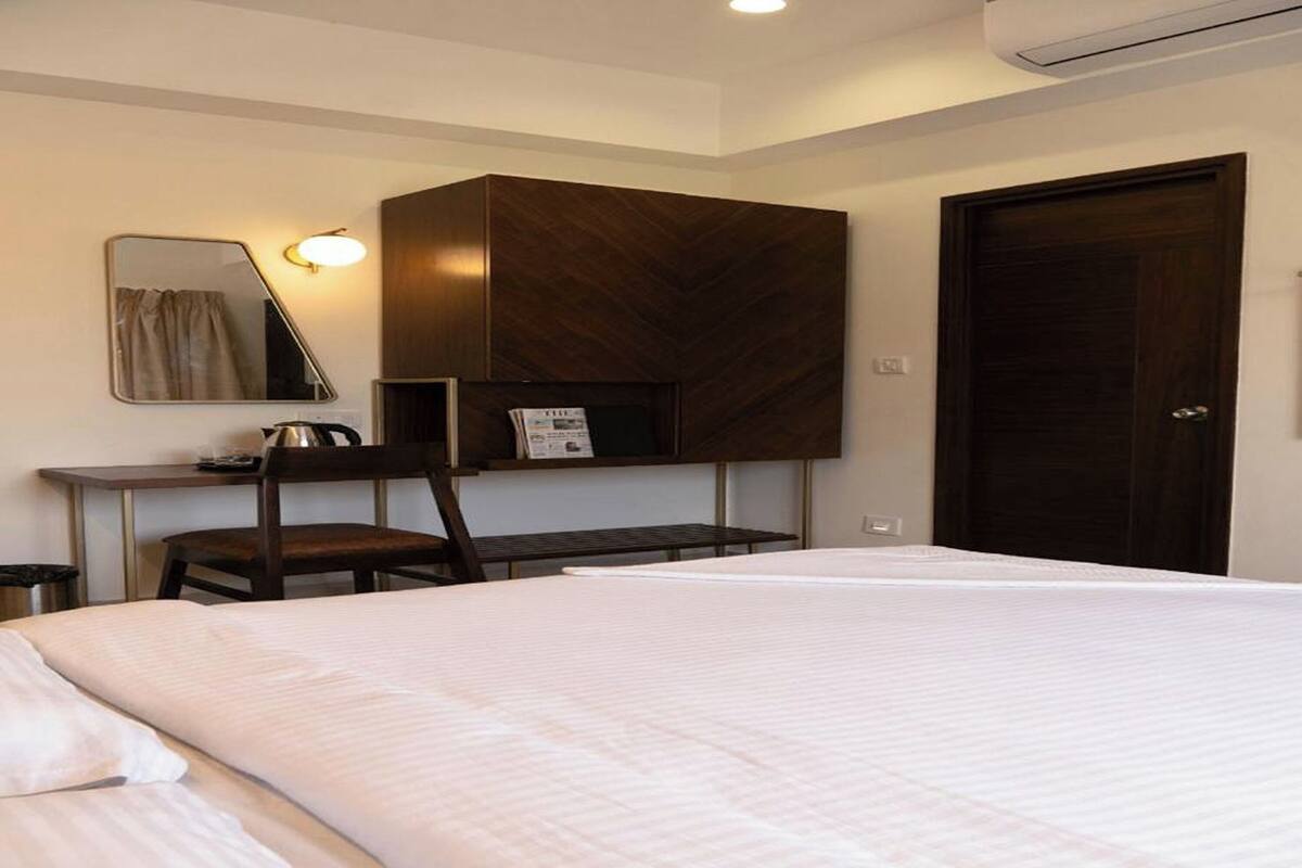 A hotel room with a bed, a desk, a chair, a mirror, and a wardrobe.