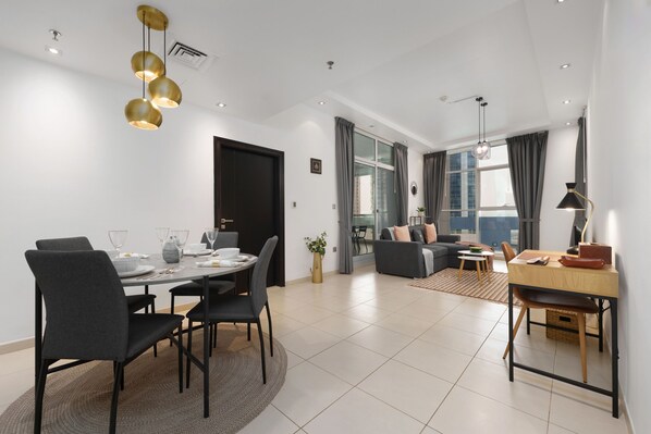 A modern living room with a dining area, featuring a sofa, a coffee table, and a dining table set with chairs.