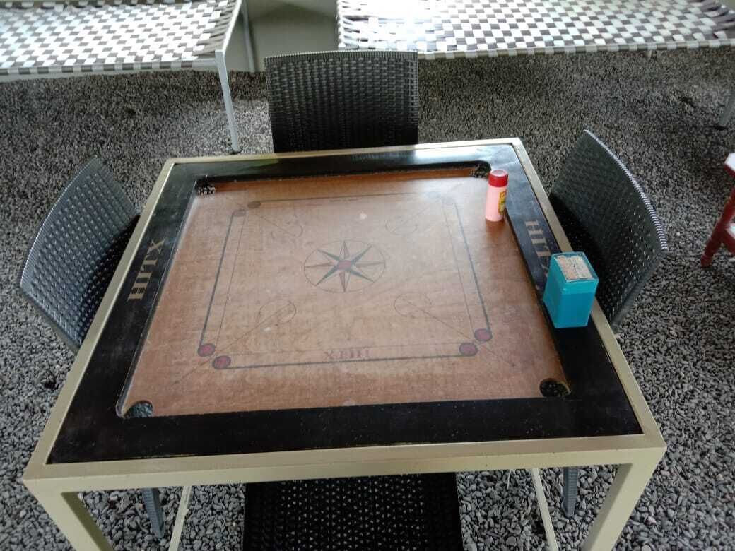 Une table carrée posée sur un sol à carreaux, avec un motif en étoile au centre et un petit objet bleu sur le côté droit.