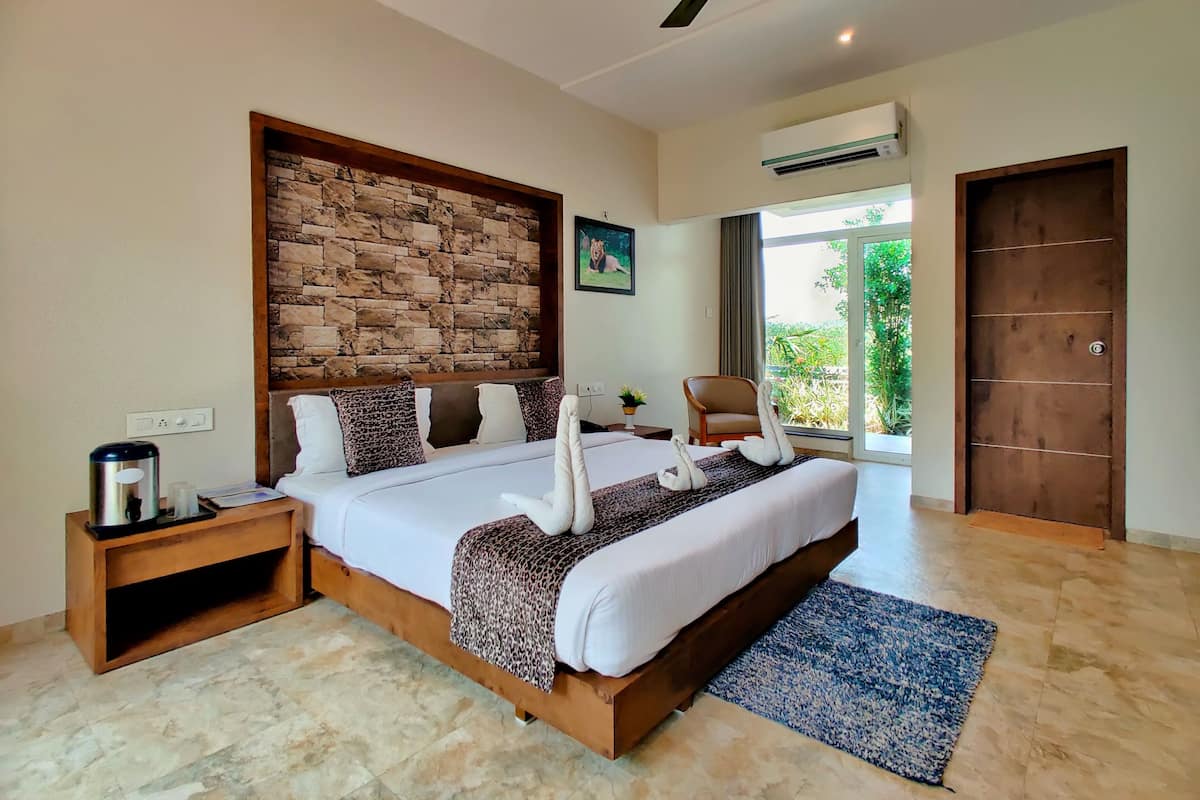 A modern bedroom with a stone accent wall, a bed with white linens and a leopard print throw, a wooden nightstand, a blue rug, and a ceiling fan.