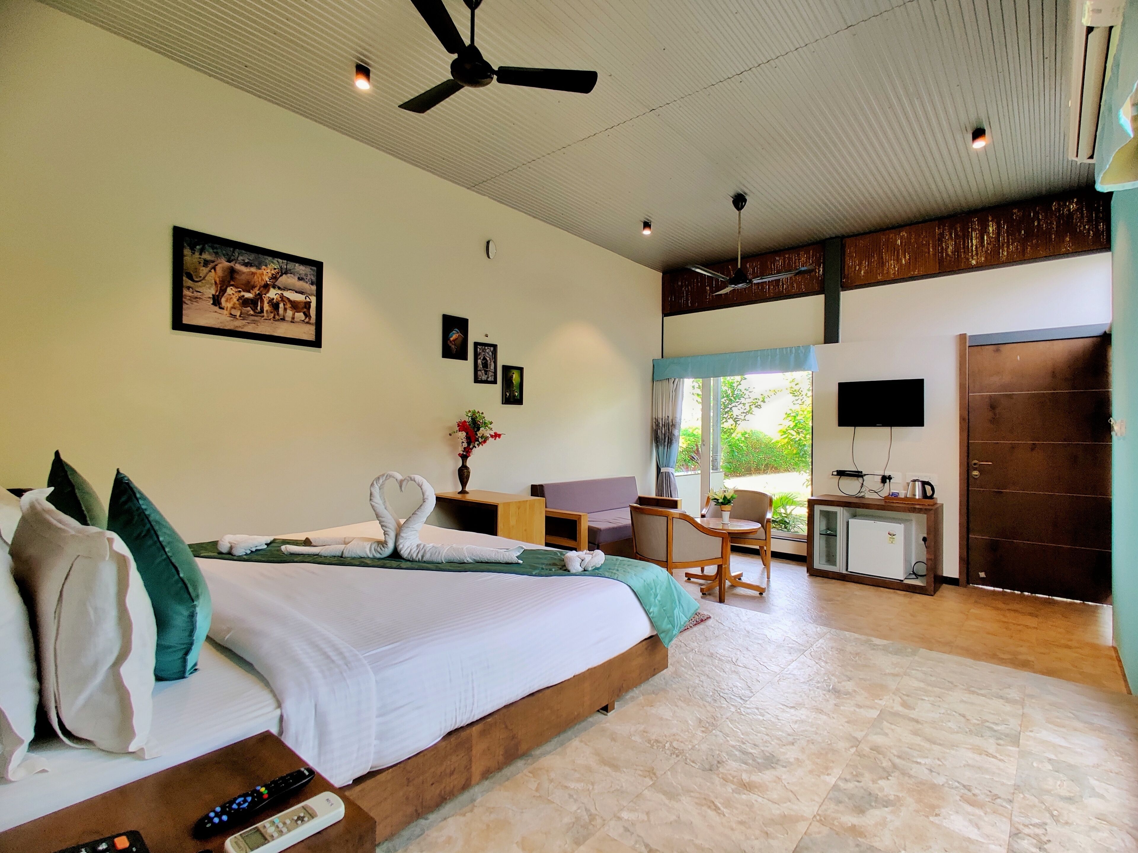 A hotel room with a bed, a desk, a chair, a TV, and a door.