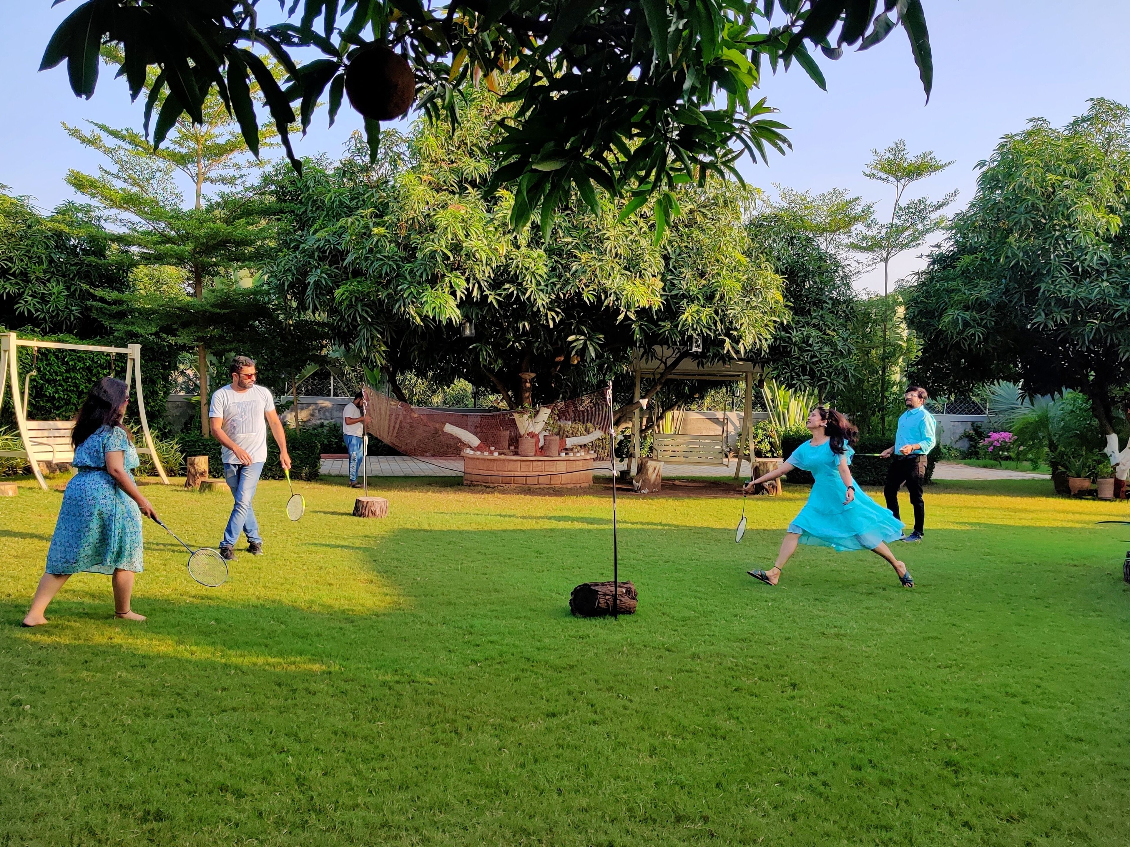 A grassy outdoor area with a swing set, benches, and a wooden structure.
