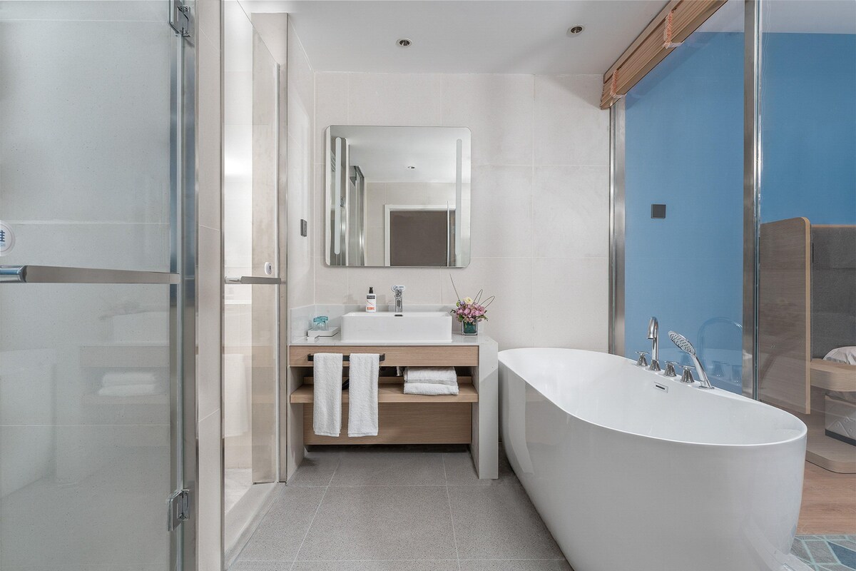 A modern bathroom with a freestanding bathtub, a large mirror, and a glass shower enclosure.