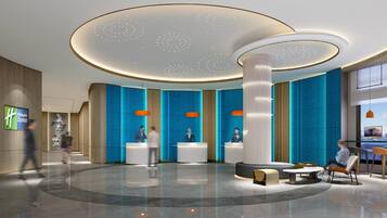 En moderne hotellobby med en central receptionsdisk, siddeområder og en stor søjle.
