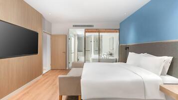 A modern hotel room with a bed, bedside table, and a TV mounted on the wall.
