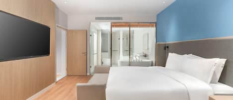 Una habitación de hotel moderna con una cama, una mesita de noche y un televisor montado en la pared.