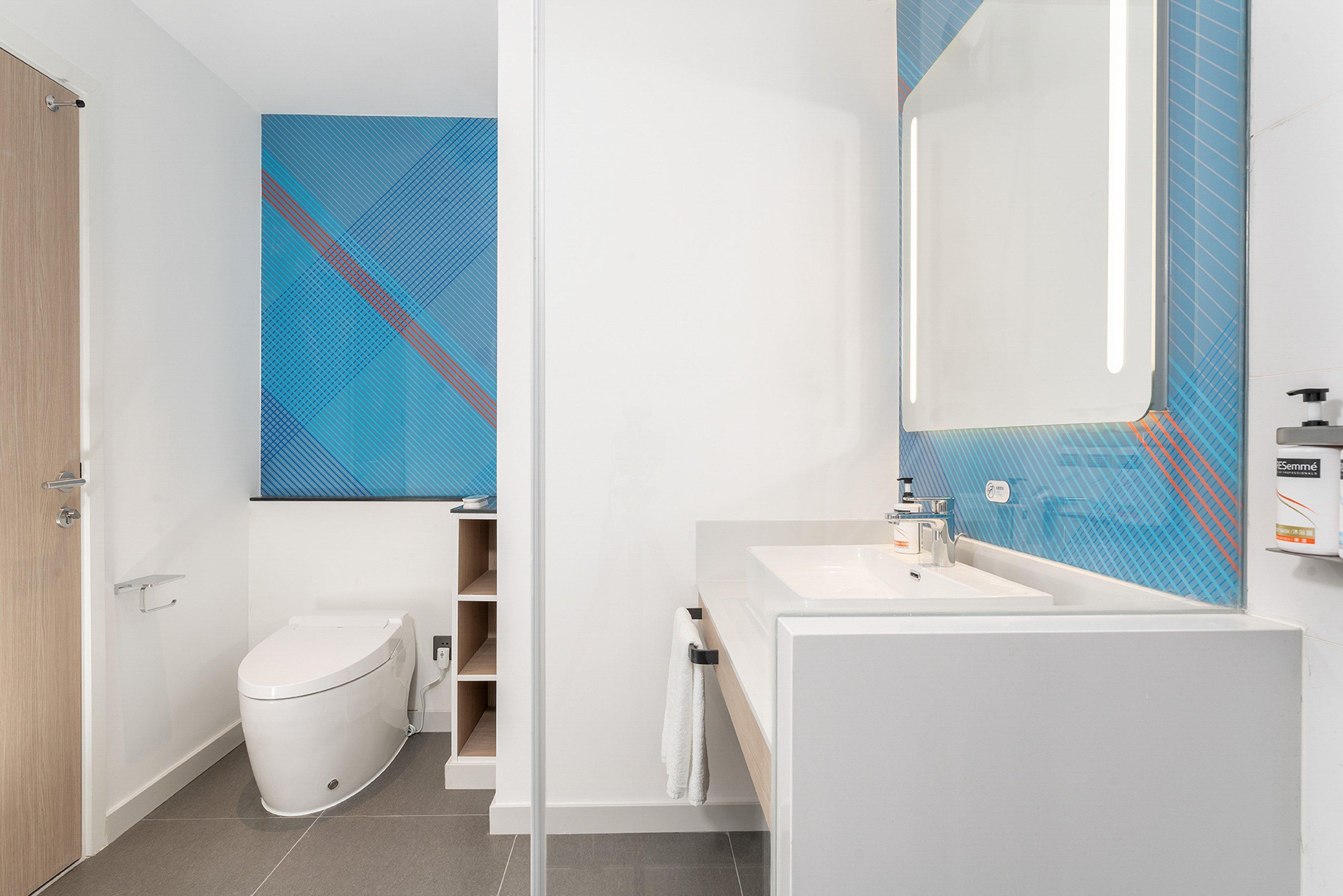 A modern bathroom with a toilet, sink, and mirror.