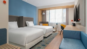 A hotel room with two beds, a sofa, a small table, a chair, a TV, and a window with curtains. - Holiday Inn Express Dandong City Center (Dandong)