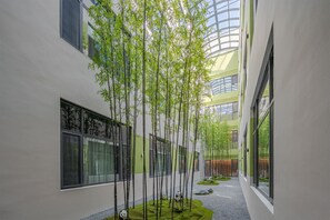 A building with a modern architectural design, featuring a central courtyard with bamboo trees and a small pond. - Holiday Inn Express Dandong City Center (Dandong)
