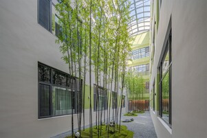 A building with a modern architectural design, featuring a central courtyard with bamboo trees and a small pond.