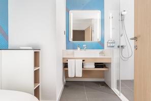 A modern bathroom with a shower, a sink, and a mirror.