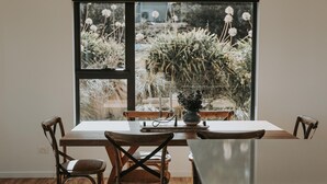 A dining table with chairs, a vase with flowers, and a candle. - Tranmere Seaside Serenity (Tranmere)