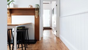 A hallway with wooden flooring, white walls, and a wooden counter with stools.