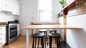 A kitchen with white cabinets, a wooden countertop, a built-in oven, and three black stools.
